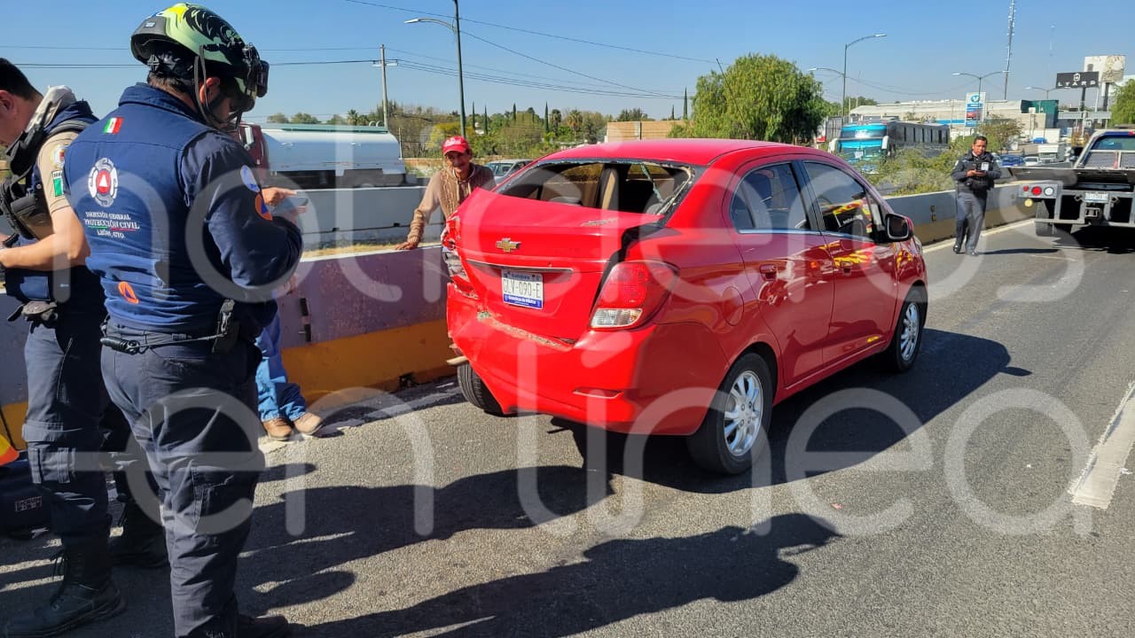 León, Gto. — La mañana de este día se registró un choque múltiple en la parte alta del puente ubicado en el cruce del bulevar Aeropuerto y La Herradura, lo que generó una intensa movilización de cuerpos de emergencia y el cierre total de la circulación en la zona. En el lugar se encuentran elementos de Protección Civil, Bomberos y la Cruz Roja Mexicana, quienes atienden el reporte en el que se vieron involucrados al menos cuatro vehículos: un camión de pasajeros de turismo, un camión de carga que transportaba láminas y dos camionetas particulares. De acuerdo con la información preliminar, uno de los conductores quedó atrapado al interior de su unidad, por lo que fue necesario el uso de equipo hidráulico para su liberación. La persona ya fue rescatada y trasladada en ambulancia para recibir atención médica. Asimismo, rescatistas se mantienen en el sitio para liberar y valorar a los pasajeros del camión de turismo. El camión de pasajeros presenta severos daños en la parte frontal, incluida una llanta completamente destrozada, lo que evidencia la magnitud del impacto. Debido al accidente, la circulación del puente de La Herradura con dirección de Silao hacia León permanece completamente cerrada. El tránsito está siendo desviado por las vialidades laterales, lo que ha ocasionado afectaciones importantes a la movilidad, por lo que se exhorta a los automovilistas a tomar precauciones y buscar rutas alternas. Las autoridades continúan trabajando en la zona y se espera que en las próximas horas se brinde mayor información sobre el estado de salud de los involucrados y las causas del accidente.